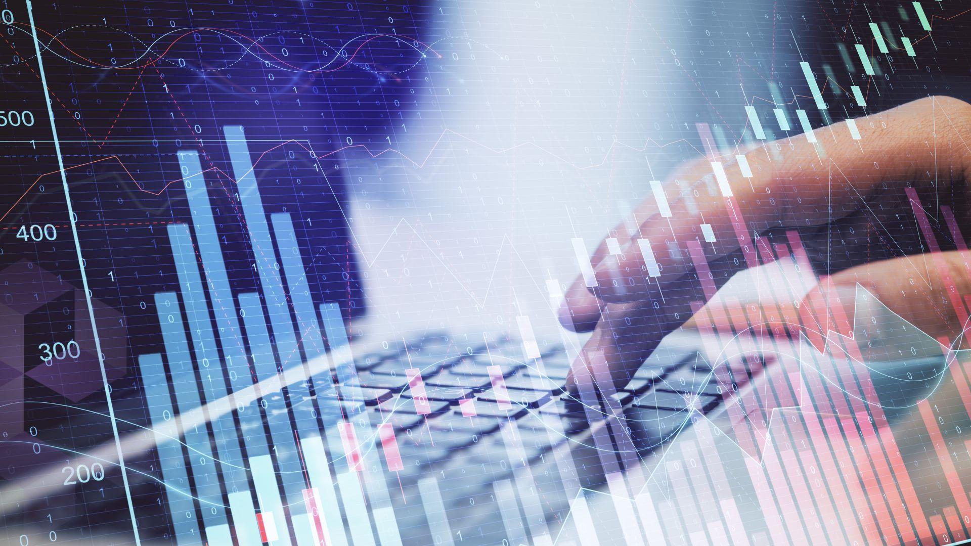 hand on keyboard over stock market graphs