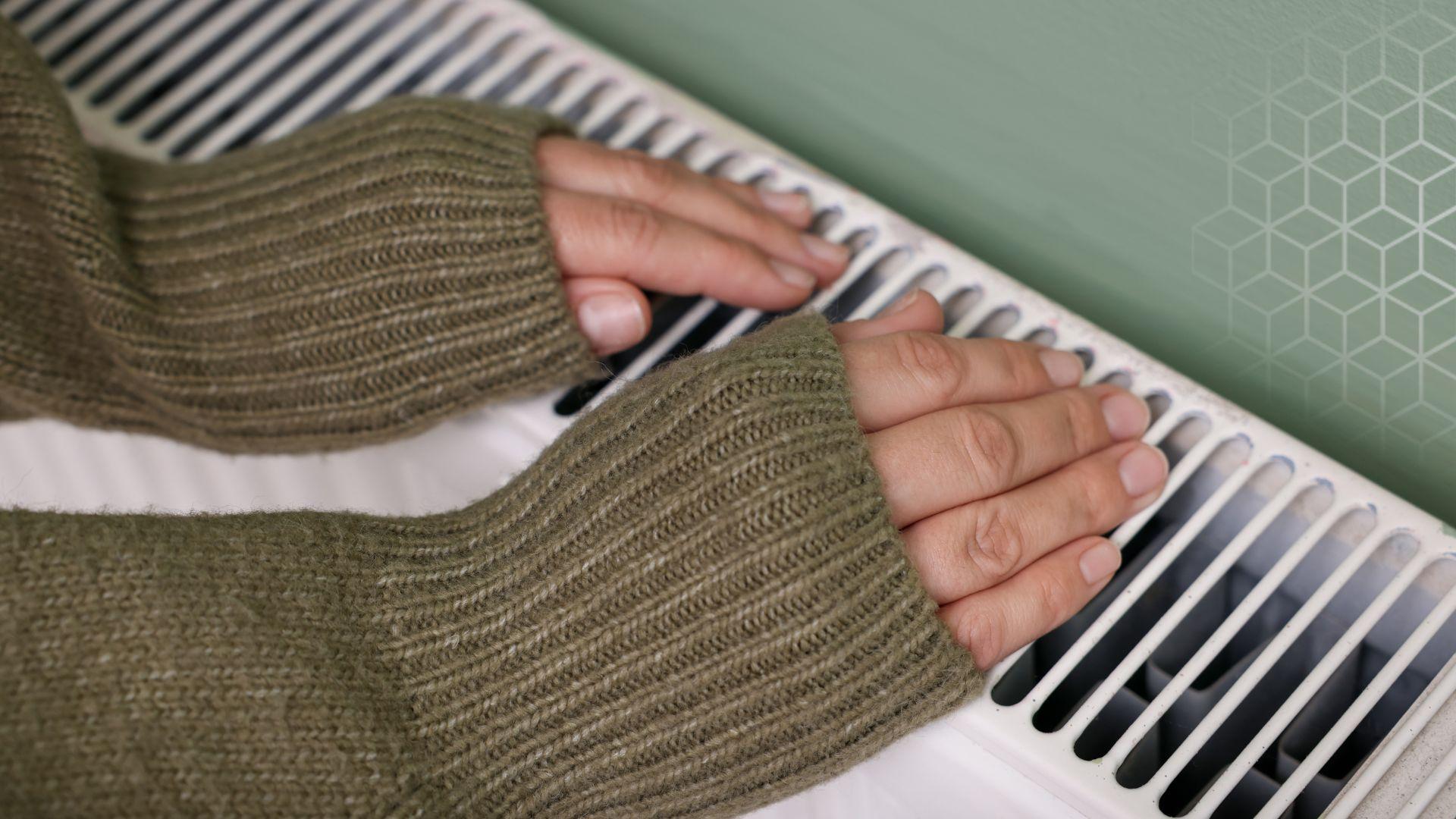 Two hands rest on a radiator