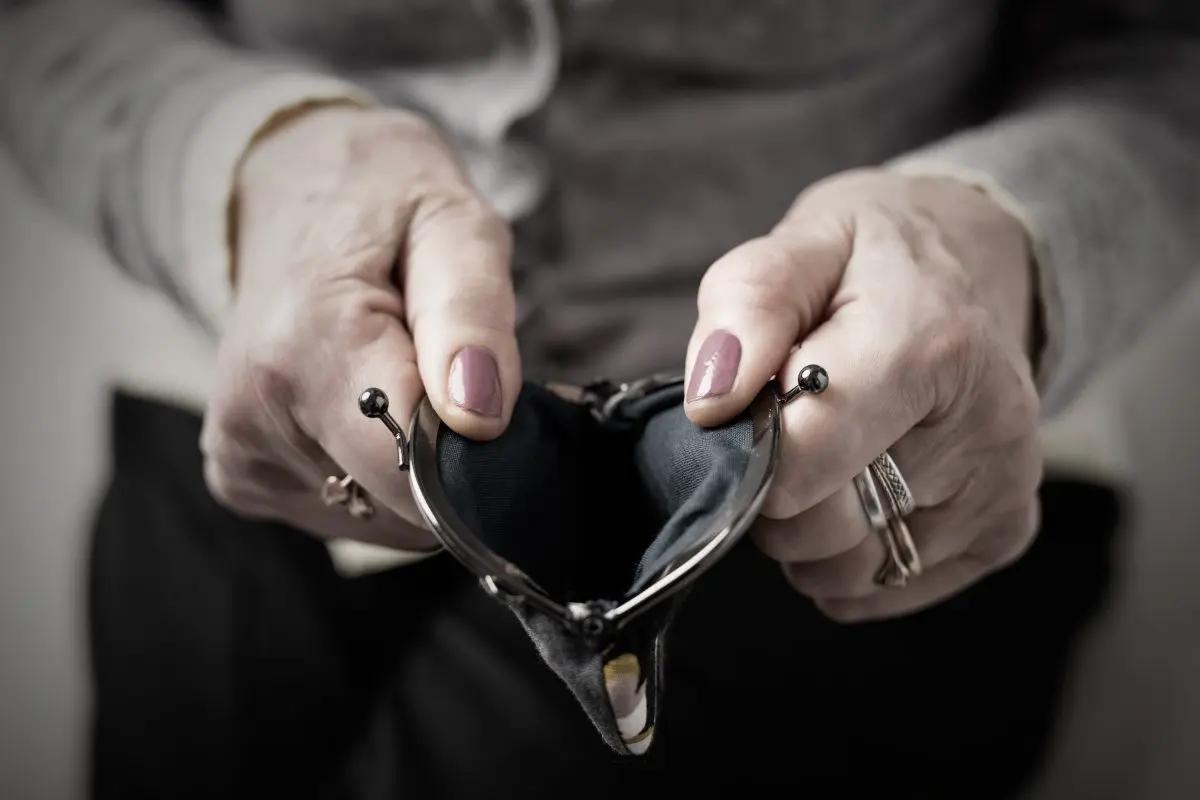 Older ladies hands holding an empty purse open